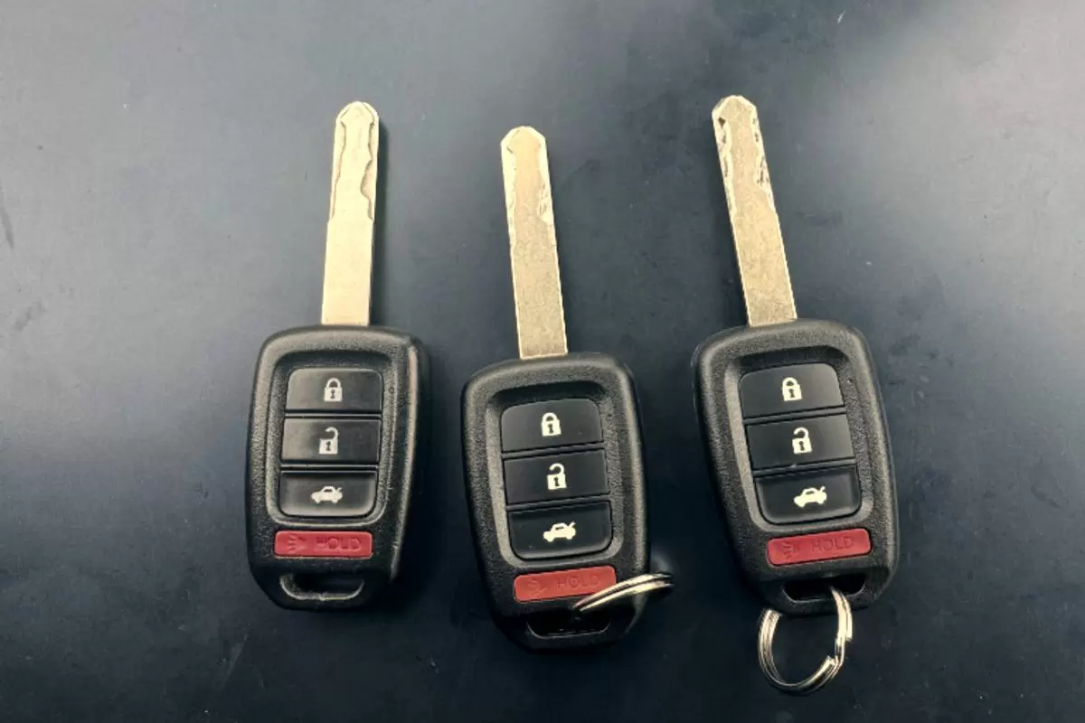 Three cut Honda remote head keys laid side by side on a dark work surface, blades freshly milled.